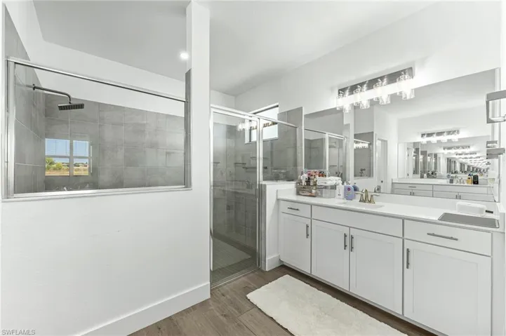 Full bathroom featuring a stall shower, vanity, and light wood-style floors