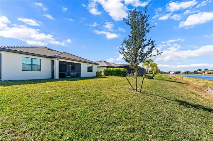 View of grassy yard with a sunroom and a water view
