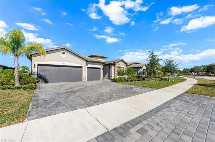 View of front of home featuring a front lawn, stucco siding, decorative driveway, a garage, and stone siding