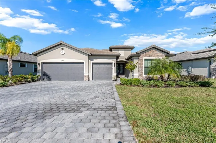 View of front of house with stone siding, a front lawn, decorative driveway, a garage, and stucco siding