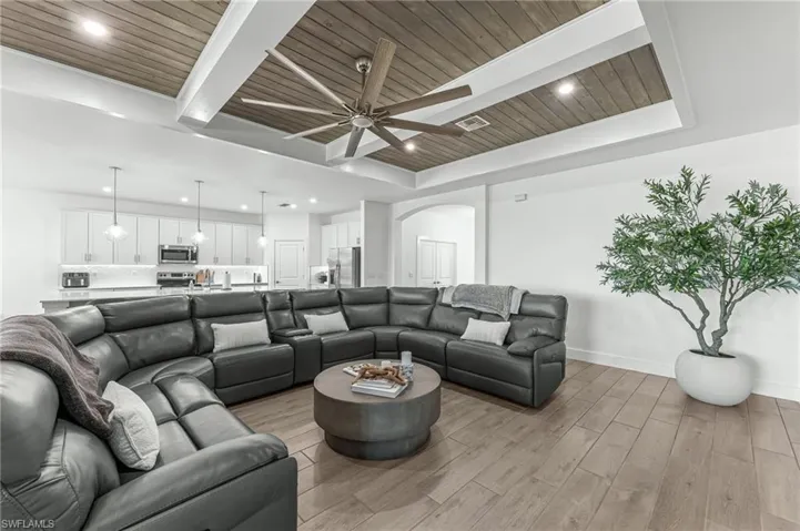 Living area with light wood finished floors, a wood ceiling with exposed beams, arched walkways, recessed lighting, and ceiling fan