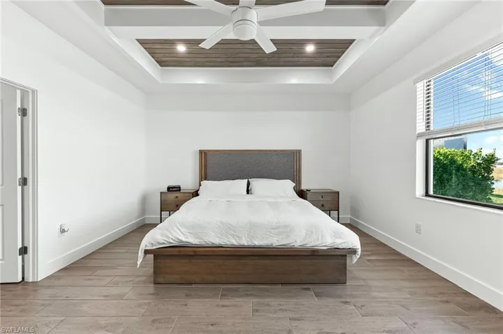 Bedroom with wood finish floors, ceiling fan, and a tray ceiling