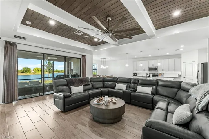 Living area featuring a water view, a wood ceiling with exposed beams, wood finish floors, recessed lighting, and ceiling fan