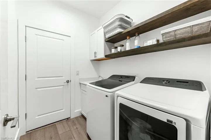 Laundry room with light wood finished floors, independent washer and dryer, and cabinet space