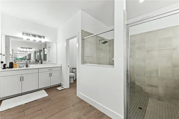 Full bath with a walk in shower, vanity, and light wood finished floors