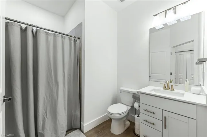 Bathroom featuring a shower stall, vanity, and dark wood-type flooring