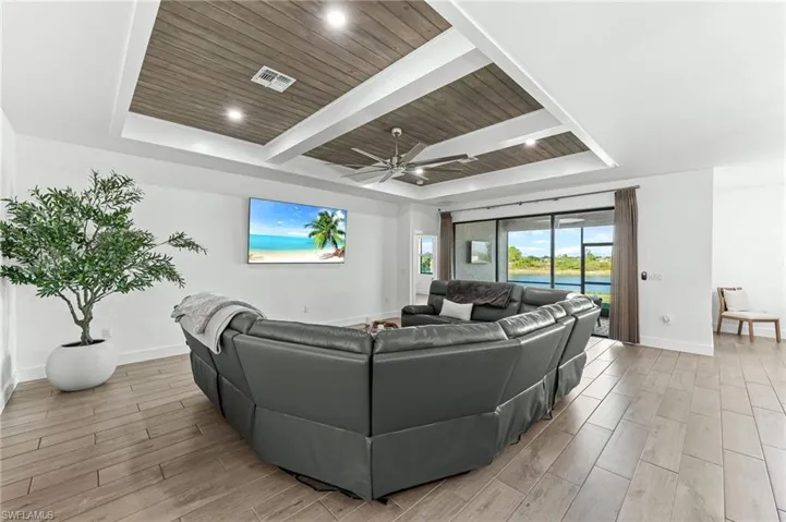 Living area with a tray ceiling, wood tiled floors, wooden ceiling, and a ceiling fan
