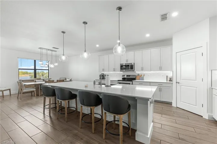 Kitchen featuring white cabinets, hanging light fixtures, a kitchen breakfast bar, and recessed lighting