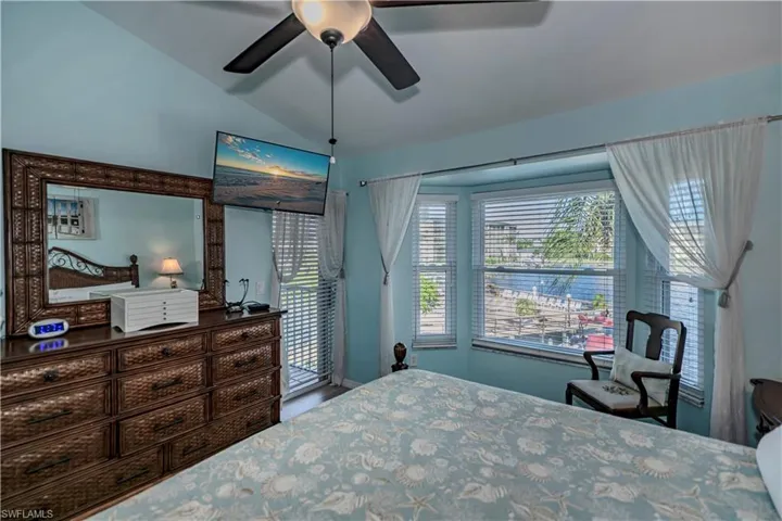 Bedroom with multiple windows, lofted ceiling, and ceiling fan