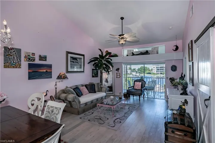 Living room with high vaulted ceiling, hardwood / wood-style floors, and ceiling fan with notable chandelier