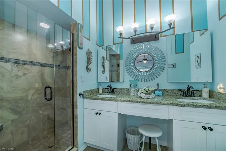 Bathroom featuring dual vanity and a shower with door