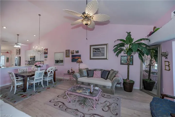 Living room featuring high vaulted ceiling, light wood-type flooring, and ceiling fan with notable chandelier