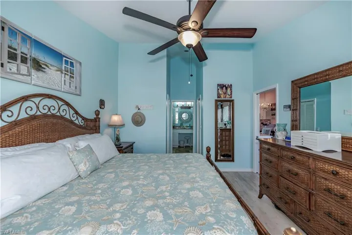 Bedroom with ceiling fan, ensuite bathroom, a towering ceiling, and hardwood / wood-style flooring