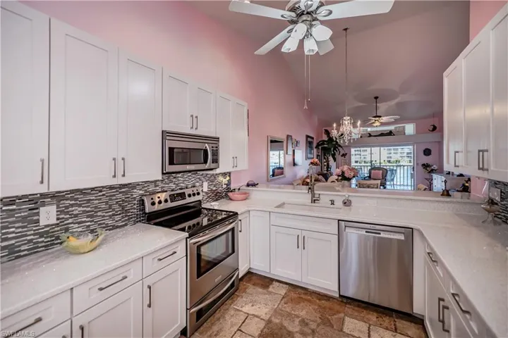 Kitchen featuring ceiling fan, stainless steel appliances, light tile flooring, and white cabinetry
