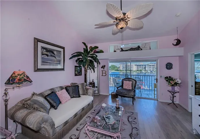 Living room with high vaulted ceiling, ceiling fan, and hardwood / wood-style flooring