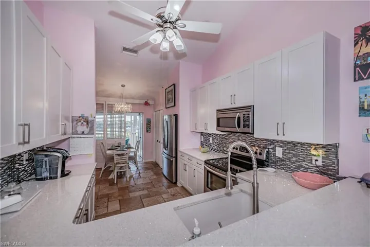 Kitchen featuring decorative light fixtures, tasteful backsplash, appliances with stainless steel finishes, light tile floors, and lofted ceiling