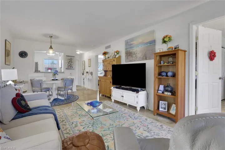 Open-concept living area featuring light-toned flooring, white walls, and a dedicated dining space with an overhead pendant light