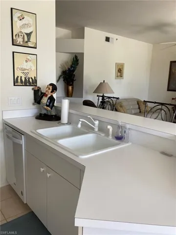 Kitchen featuring stainless steel dishwasher, a sink, light countertops, and light tile patterned floors