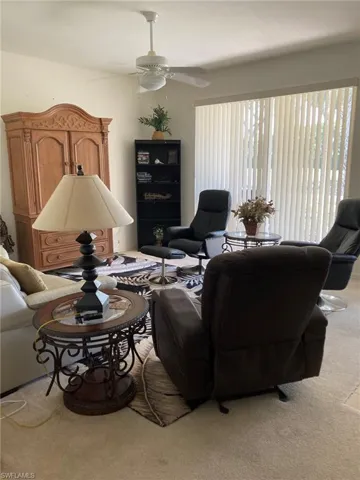 Carpeted living room with a ceiling fan