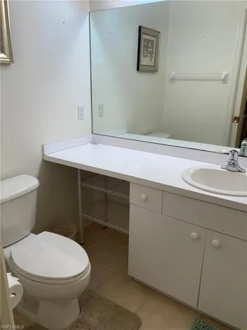 Half bath featuring toilet, vanity, and tile patterned flooring