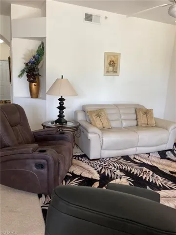 Carpeted living room with arched walkways