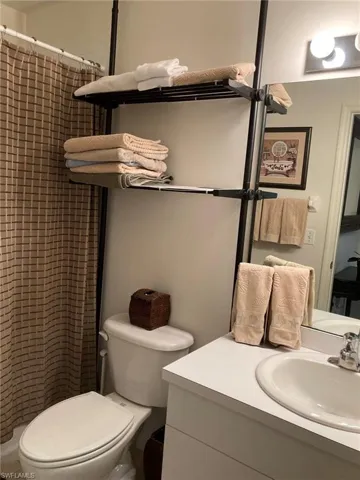 Full bathroom featuring toilet, tiled shower, and vanity