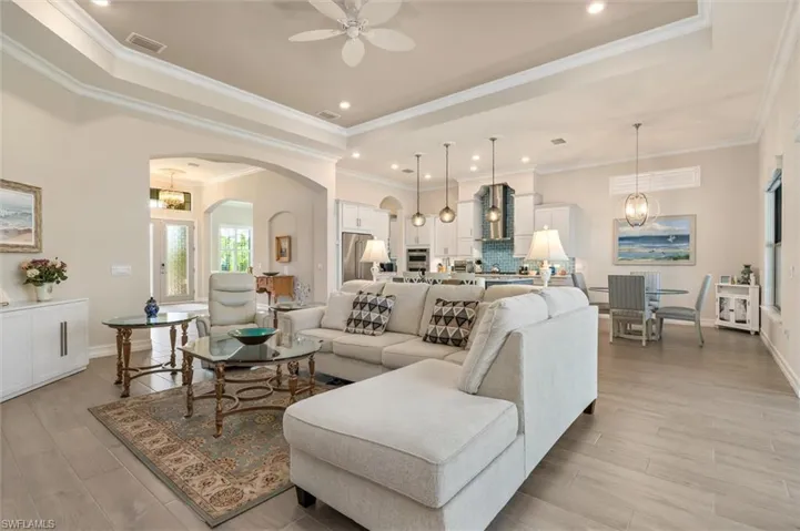 Open-concept living space featuring wood-finish flooring, recessed lighting, and crown molding