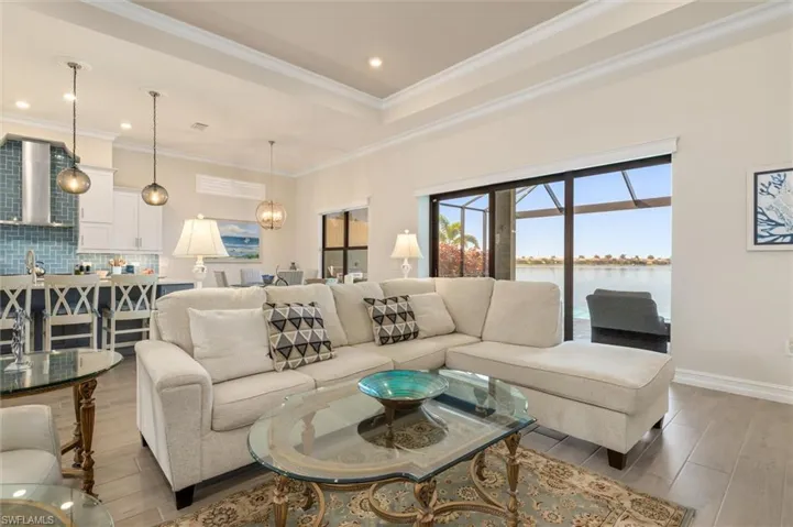 Open-concept living area featuring wood-finish flooring, crown molding, and recessed lighting