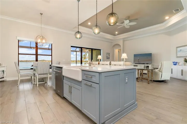 Spacious kitchen island featuring light grey cabinetry and a white farmhouse sink