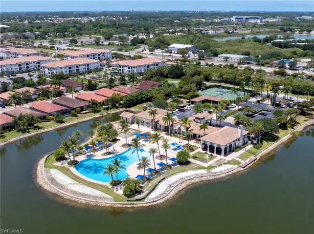 Expansive community grounds featuring multiple buildings, a large lagoon-style pool with surrounding lounge chairs, and mature palm trees
