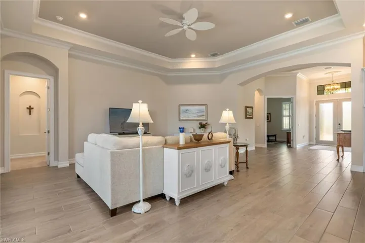 Spacious living area featuring wood-finish flooring, a tray ceiling with crown molding, and recessed lighting