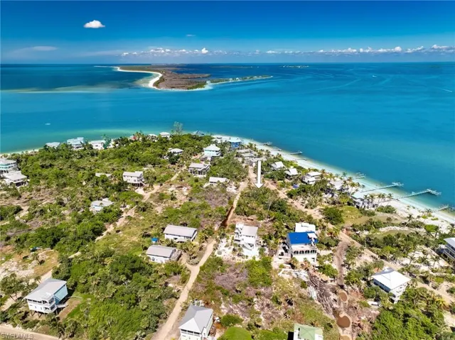Birds eye view of property featuring a water view and a view of the beach