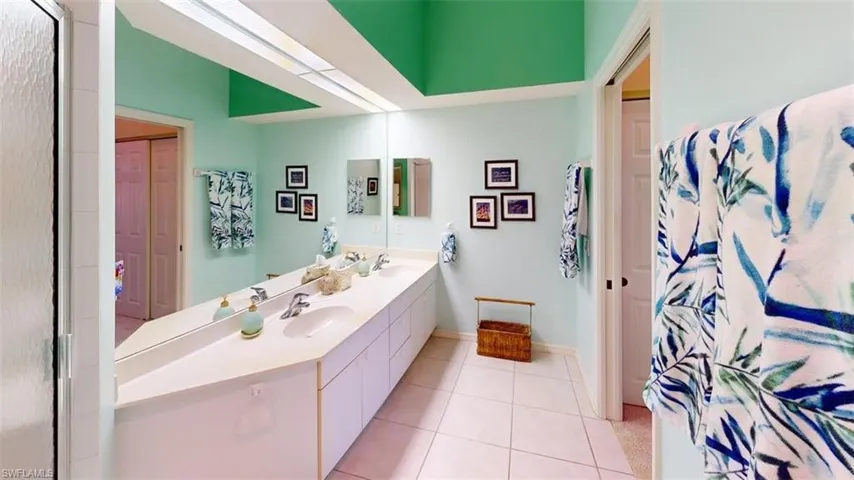 Full bathroom with double vanity, light tile patterned floors, and curtained shower