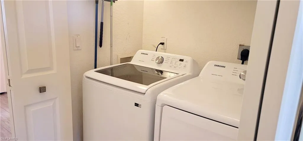 Laundry area with a textured wall and washer and clothes dryer