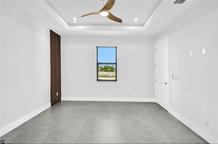Unfurnished room with crown molding, ceiling fan, and a raised ceiling