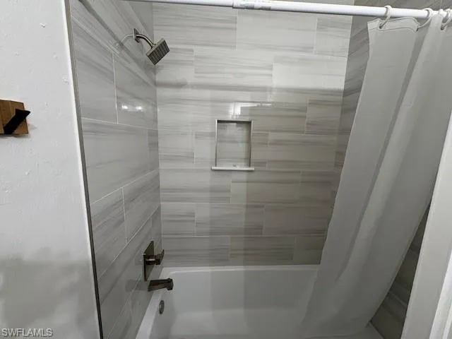 Full bath featuring shower / tub combo and a textured wall