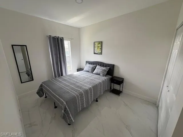 Bedroom with light marble finish floors and a closet