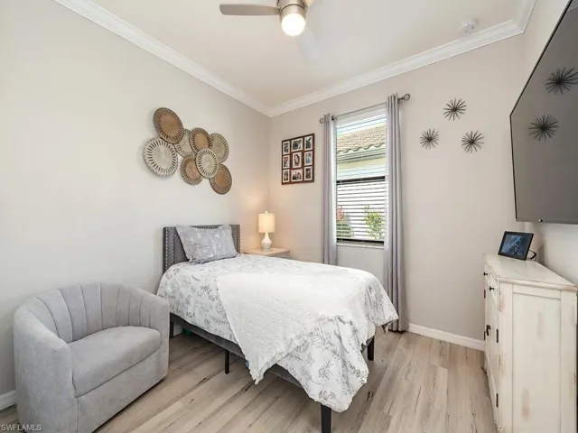Bedroom featuring ceiling fan, ornamental molding, light wood-style flooring, and baseboards