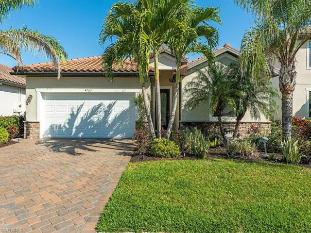 Mediterranean / spanish house featuring an attached garage, a tiled roof, decorative driveway, stucco siding, and a front lawn