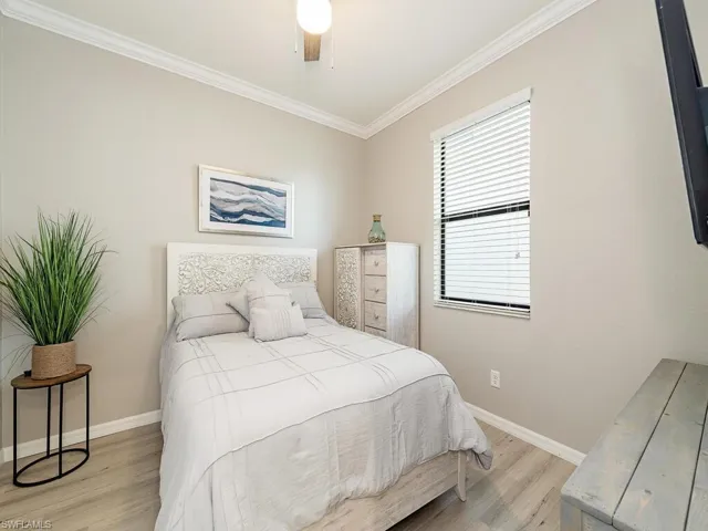 Bedroom featuring baseboards, a ceiling fan, light wood-style flooring, and crown molding