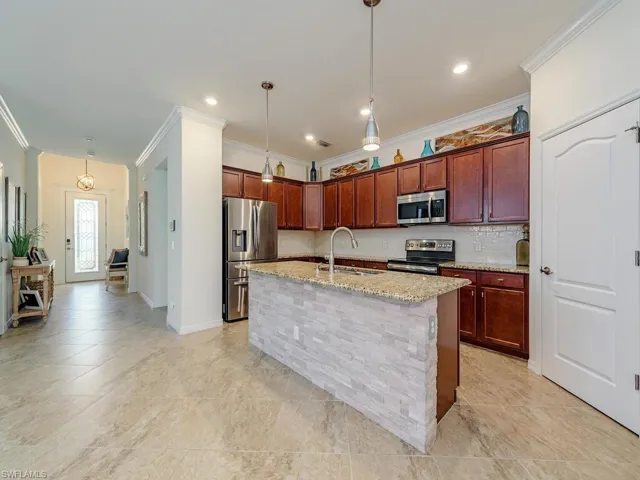 Kitchen with ornamental molding, a sink, light stone countertops, stainless steel appliances, and backsplash