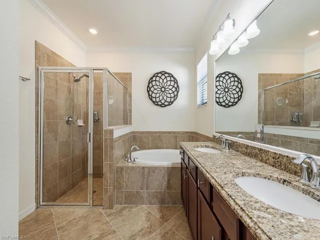 Bathroom with a stall shower, a sink, a bath, and crown molding