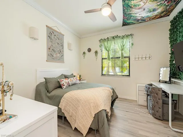 Bedroom featuring light wood-style floors, ceiling fan, baseboards, and crown molding