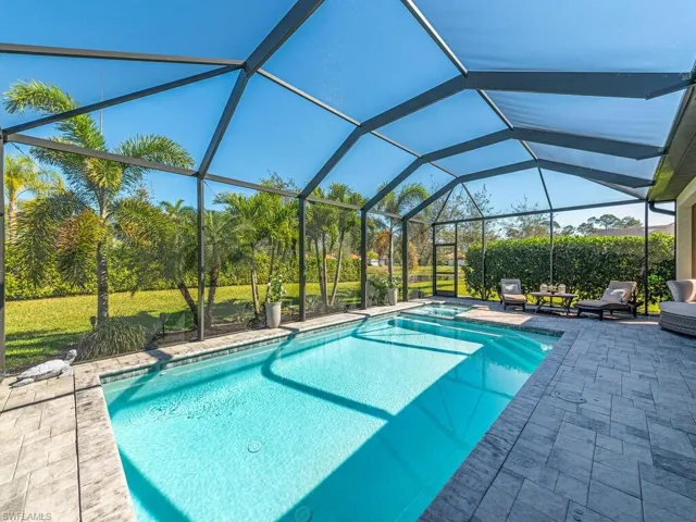 View of pool with a yard, a lanai, a patio area, and a pool with connected hot tub