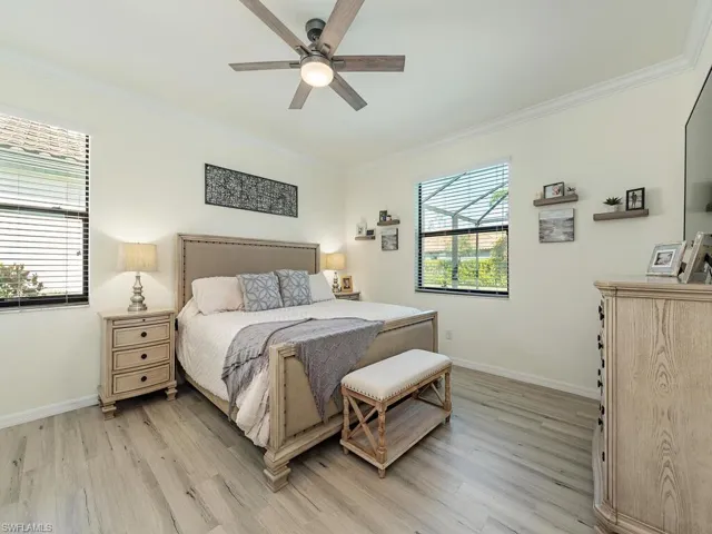 Bedroom featuring ornamental molding, light wood-type flooring, multiple windows, and baseboards