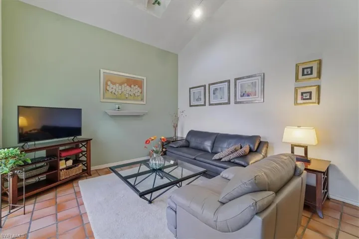Living area featuring a skylight, tile patterned flooring, and high vaulted ceiling
