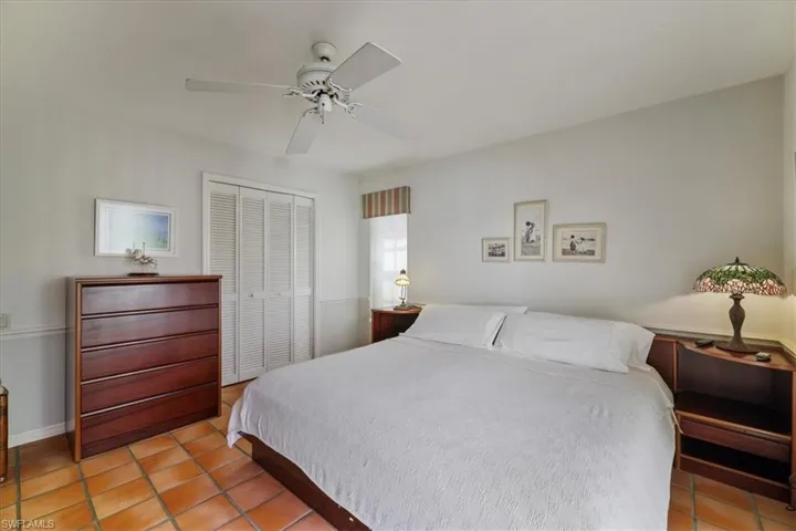 Bedroom with light tile patterned floors, a closet, and a ceiling fan