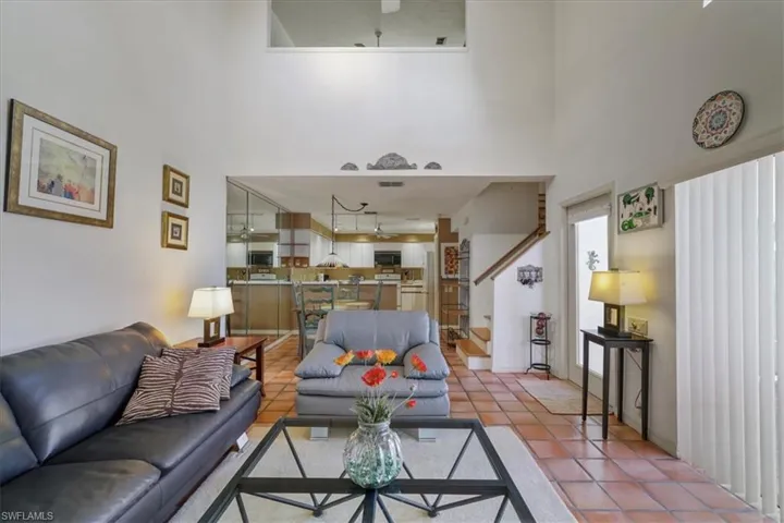Living area with a high ceiling, tile patterned flooring, a ceiling fan, and stairs
