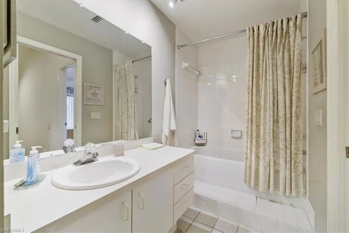Full bathroom with light tile patterned floors, shower / bath combo, and vanity