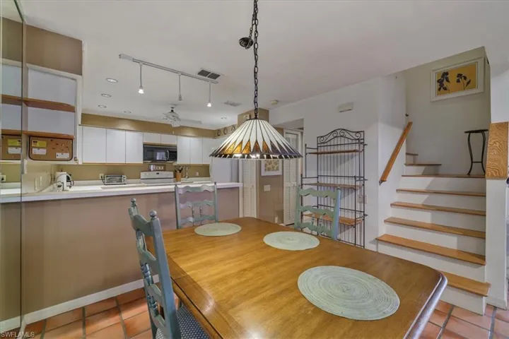 Dining room with light tile patterned floors, stairs, and a ceiling fan